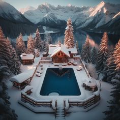 an aerial view of a house with a pool in the middle surrounded by snow covered trees