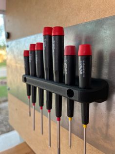 there are many screwdrivers on the wall with red caps and yellow tips in them