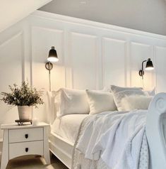 a white bed sitting in a bedroom next to two lamps on either side of it