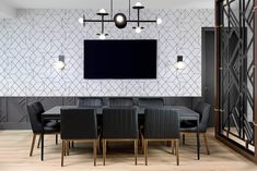 a dining room table with chairs and a television mounted on the wall above it,