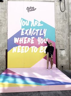 a man standing in front of a colorful wall that says you are exactly where you need to be