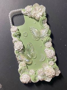 a cell phone case with flowers and butterflies on the back, sitting on a table