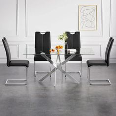 a glass dining table with four chairs and a vase filled with oranges on top