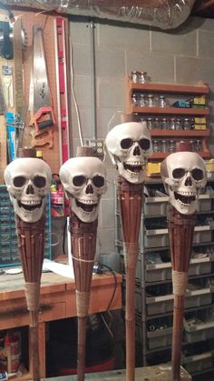 three wooden sticks with skulls on them in front of a workbench filled with tools