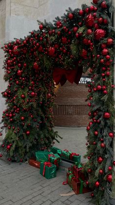 christmas decorations on the side of a building with presents under them and wrapped in red and green ribbon