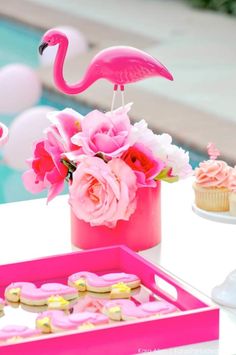 a pink flamingo themed party with cookies and cupcakes on a table next to a pool