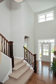 a staircase leading up to the second floor in a house with white walls and wood floors