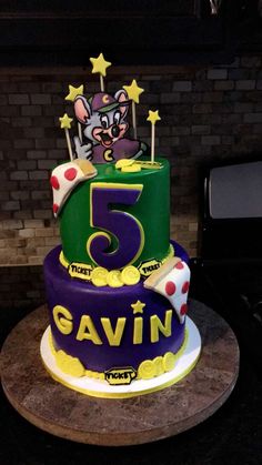 a purple and green cake with the number five on it's bottom tier is decorated with an image of a mouse