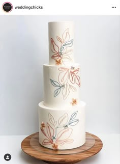 a three tiered cake with flowers painted on the side and wooden platter underneath