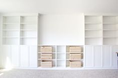 an empty room with white bookcases and drawers