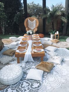 an outdoor table set up with white and brown pillows