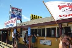 people are lined up at the outside of a seafood restaurant with umbrellas over their heads