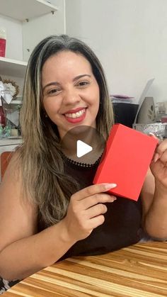 a woman sitting at a table with a red box in front of her and smiling