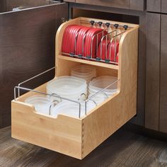 an open drawer with plates and pans in the bottom compartment, on wooden flooring