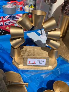 a table topped with lots of gold colored items and plates on top of blue cloth