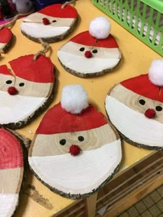 wooden slices with santa hats and pom - poms on them sitting on a table