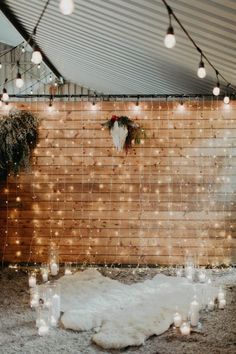 a wooden wall with lights hanging from it's sides and a rug on the floor