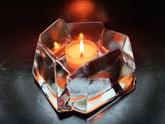 a candle that is sitting in some kind of glass holder with ice cubes around it