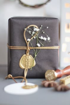 a gift wrapped in brown paper and tied with gold ribbon, sitting on a table next to other items