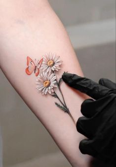 a woman's arm with daisies and butterflies on it