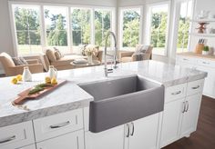 a kitchen with white cabinets and marble counter tops, along with an island in the middle