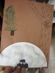 a hand holding up a paper plate with a tree on it and a black object in the middle