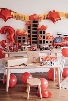 a birthday party with balloons and decorations on the table, including an orange firetruck