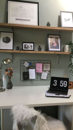 a white desk topped with a laptop computer next to a shelf filled with pictures and photos