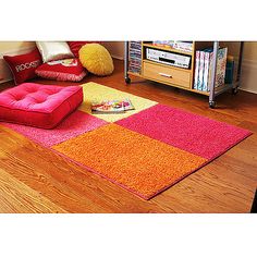 a living room with various colored rugs on the floor