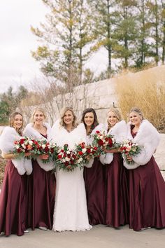 a group of women standing next to each other wearing dresses and holding bouquets in their hands