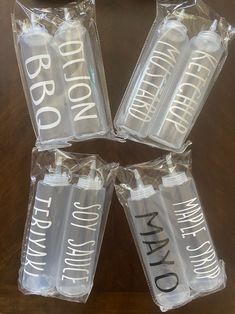 four empty water bottles sitting on top of a wooden table with plastic wrappers around them