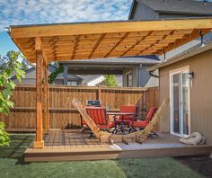 a patio with a table and chairs under a wooden pergoline over looking the backyard