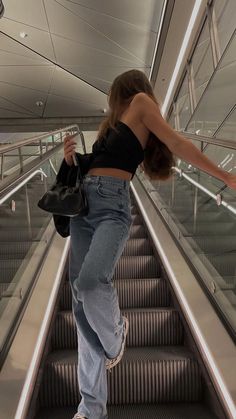 a woman is walking down an escalator with her hand in the air,