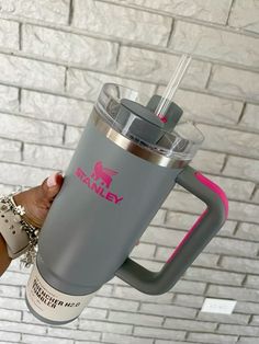 a person holding up a gray coffee cup with pink accents on it and the lid is open