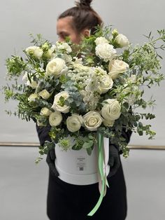 a woman holding a white bucket filled with flowers