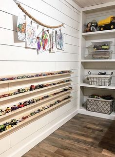 toy cars are lined up on shelves in a playroom with white walls and wood flooring