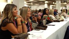 several women are sitting at tables with purses on them