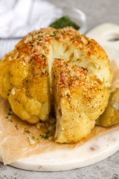 a piece of cauliflower is on a plate with a spoon and some parmesan sprinkles