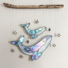 two glass dolphins hanging on a wall next to a stick and stardusted background