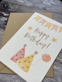 a happy birthday card with balloons and buntings on the top, sitting on a wooden table