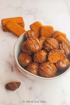 a bowl filled with chocolate covered cookies on top of a white counter next to an orange peel