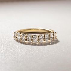 a yellow gold wedding band with five diamonds on the top and bottom, sitting on a white surface