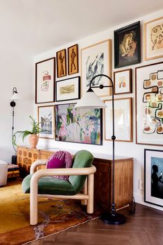 a living room filled with lots of framed pictures on the wall above a green chair