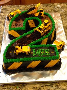 there is a birthday cake made to look like a number two with construction vehicles on it