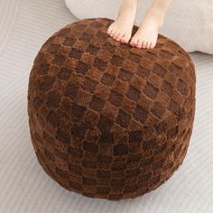 a person standing on top of a brown and white pouffle bean bag chair