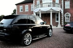 a black range rover parked in front of a house