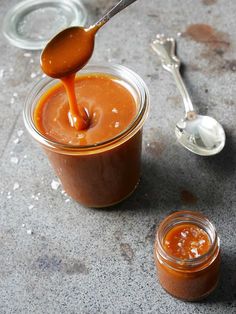 a spoon pouring caramel sauce into a jar