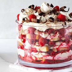 a layered dessert in a glass dish with strawberries and chocolate chips on the top