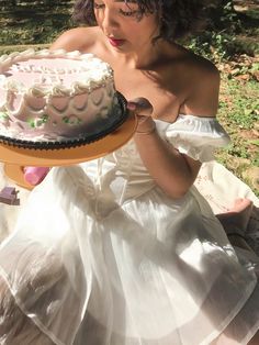 a woman in a white dress holding a cake