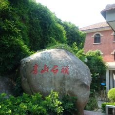 a large rock with writing on it in front of a house